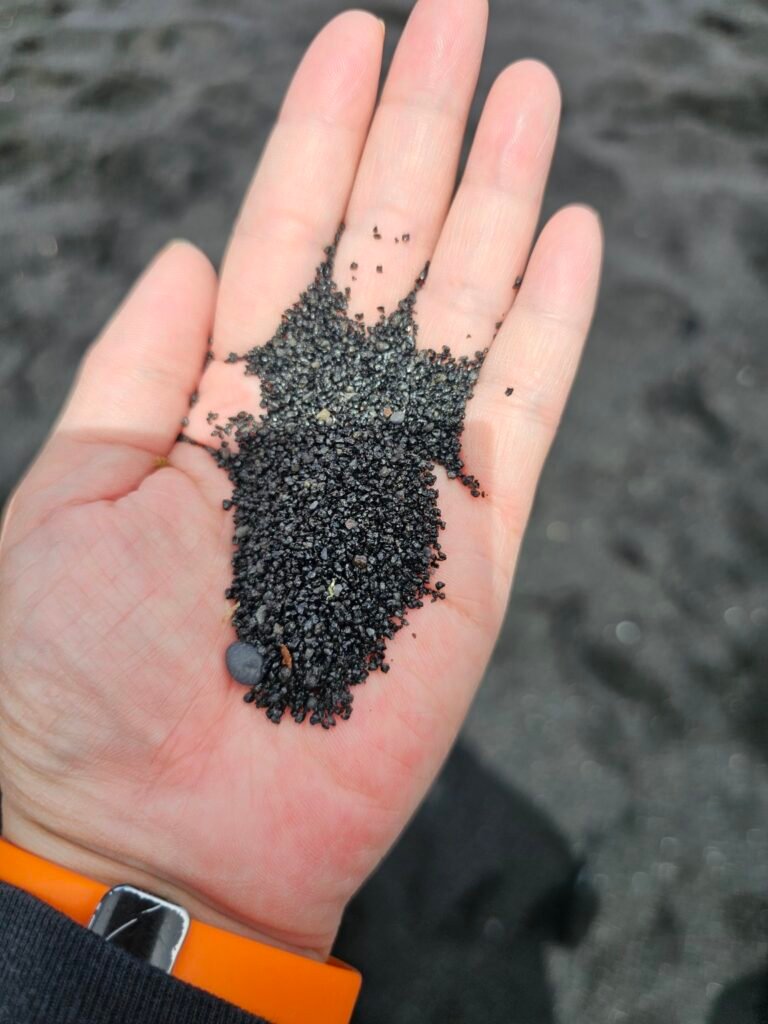 Black sand resting in a person’s hand on a Hawaii beach