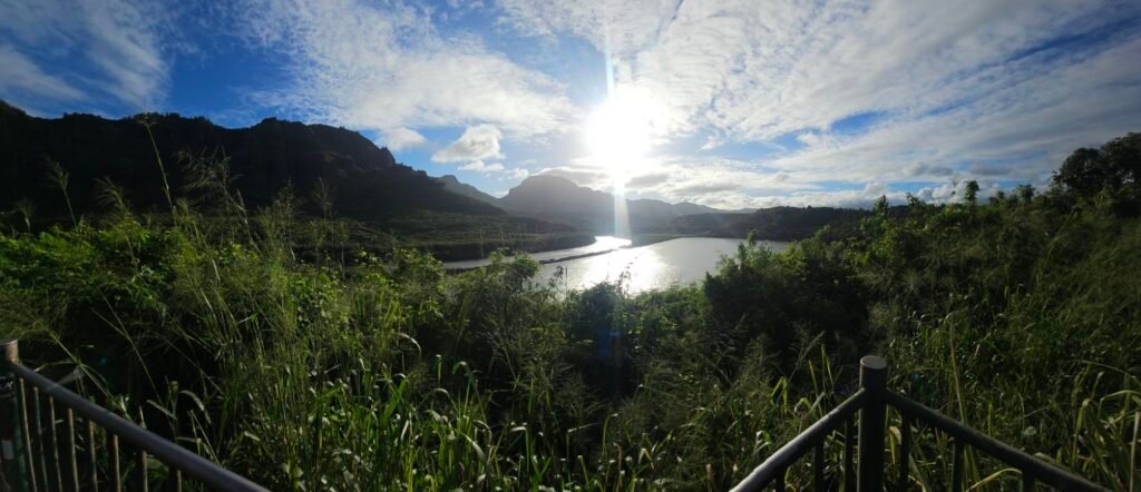 Lush green mountains and water beneath a bright sky in Hawaii