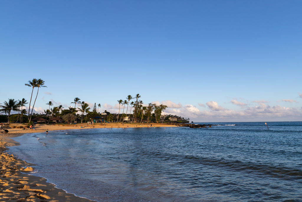 Kauaʻi Travel Guide Poʻipū Beach Park with sandy shoreline and blue ocean on Kauaʻi